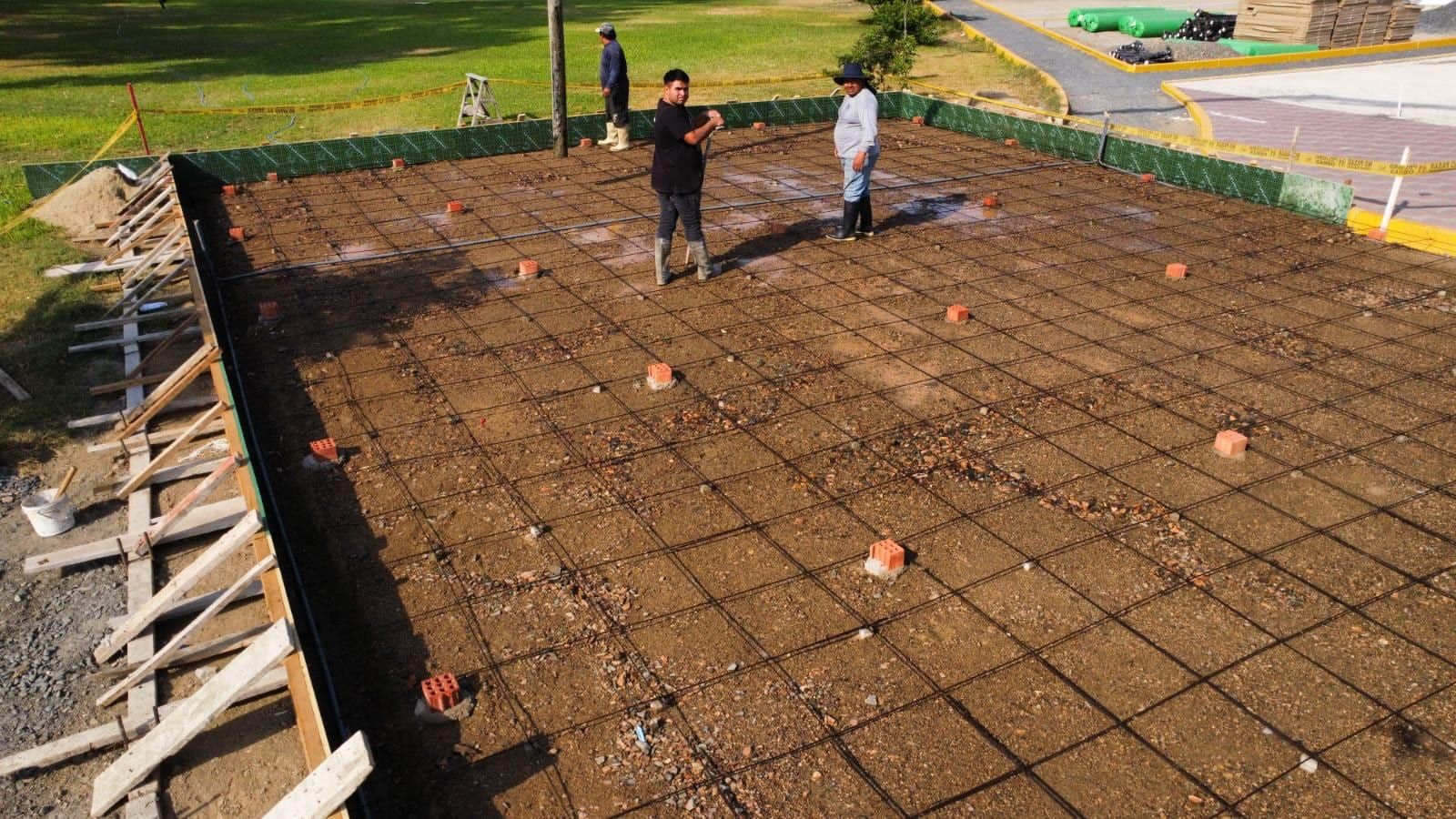 Losa de una cancha con la malla de acero tendida, el encofrado de madera y los pernos de anclaje marcados