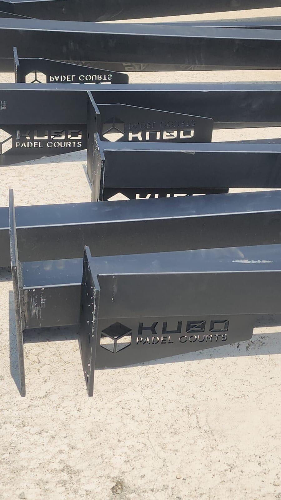 Perfiles negros de la estructura en el suelo de la obra, con el cubo y la palabra KUBO calados en sus placas